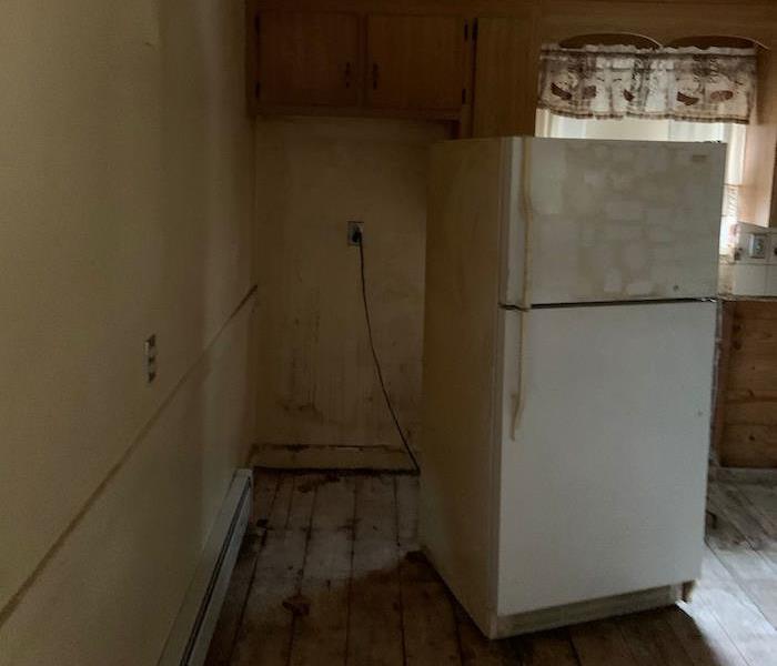 Dirty walls and floor with fridge away from the wall