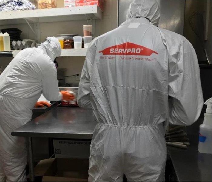 SERVPRO techs, donned in PPE, cleaning a commercial kitchen