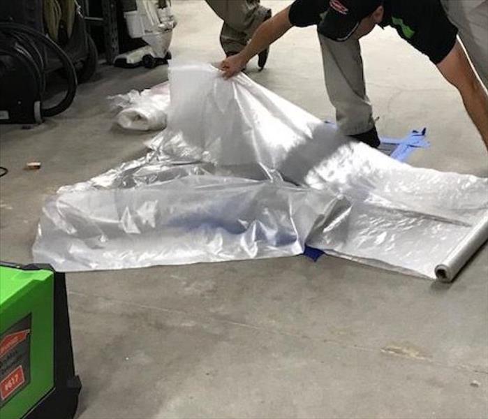 A SERVPRO employee unwrapping plastic from the floor. 