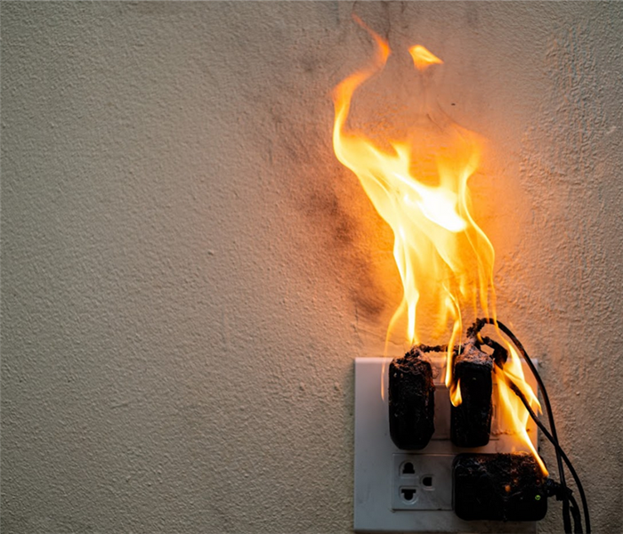a wall outlet with things plugged in that are on fire